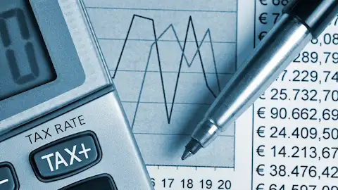Uma calculadora com a tecla &amp;amp;amp;quot;TAX+&amp;amp;amp;quot; em destaque, acompanhada de gráficos financeiros e uma caneta, representando cálculos e análises tributárias.
